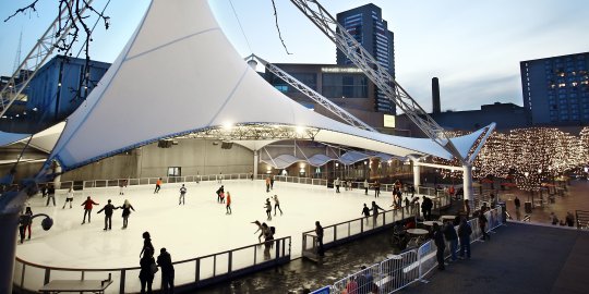 White Pavilion over ice rink with several skates; buildings in background